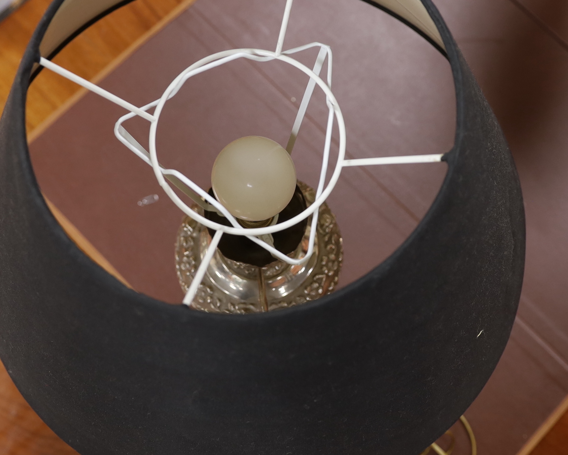 A pair of plated repousse worked table lamps with black shades, 70cm high including shades